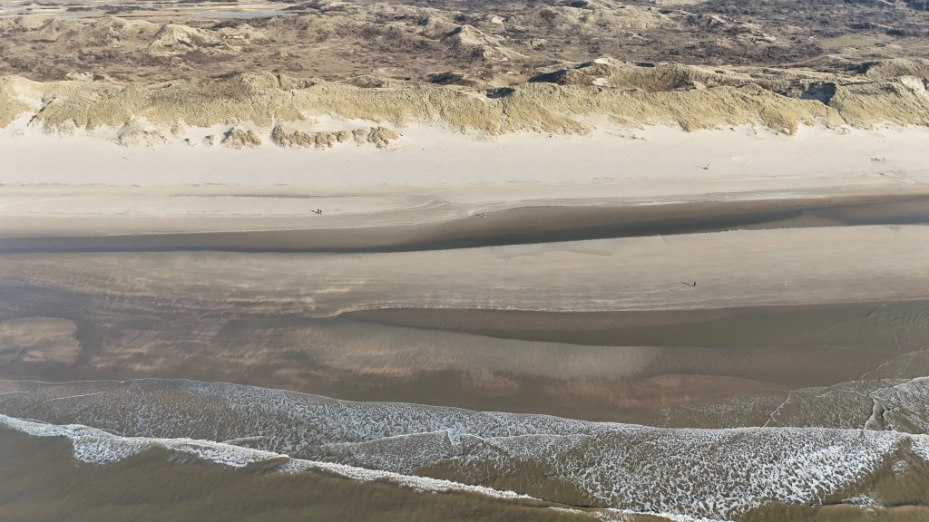 Drone footage of the beach at Wijk aan Zee. Landscape going gradually from the sea to to the beach and the dunes in the background.